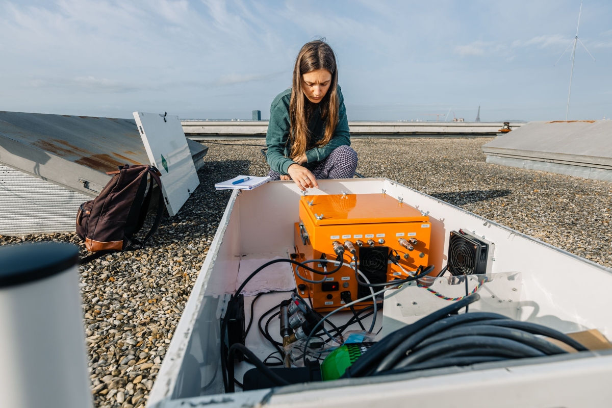 Scientist looking at a sensor on a rooftop near Paris