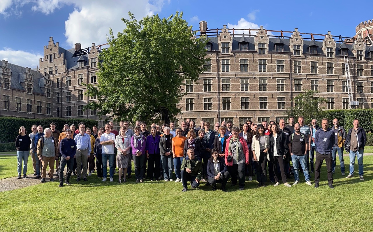 a group picture of scientists smiling in front of an   university building