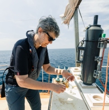 A scientist using an instument at sea.